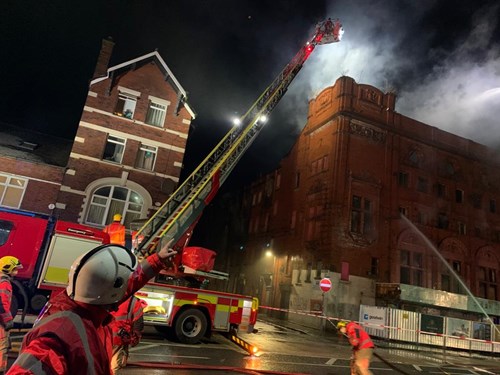 Firefighters are battling a fire at a former theatre, with smoke and emergency responders visible