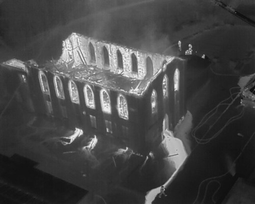Thermal image showing view from above of firefighters tackling the fire in the derelict building