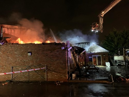 Firefighters responding to a building fire at night, with flames visible and a fire truck nearby