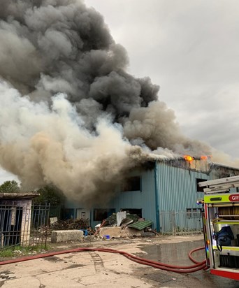 Smoke billowing from building, with fire engine in front