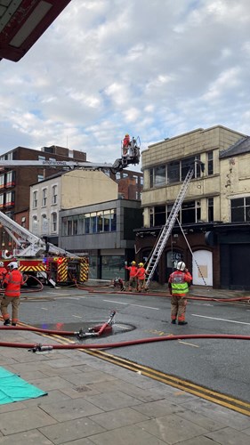 Firefighters responding to a building fire in Bolton, with a fire truck and hoses visible