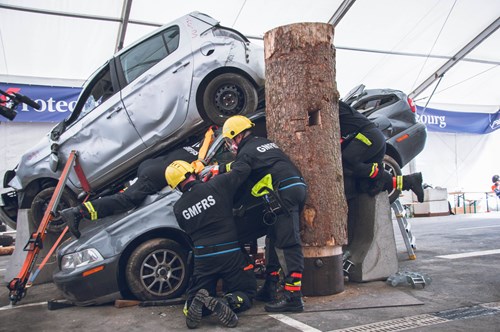 GMFRS RTC team in protective gear are working to stabilize a pile of crushed cars, with one car resting on top of another during the RTC competition exercise