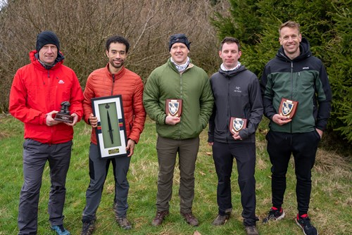 Five runners stand holding trophies