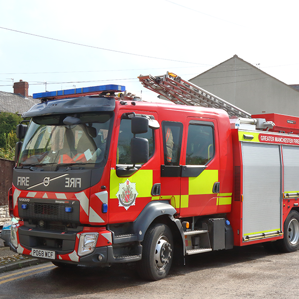 A red fire engine truck from Stretford Community Fire Station parked in front of buildings