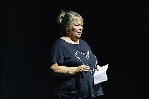 A person wearing a black top holding a piece of paper.