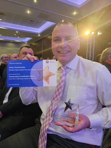 A person in a shirt and tie holding up a certificate and a trophy.