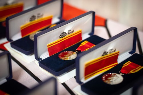 Photo shows row of Long Service Good Conduct medals in their boxes. The medals are engraved with a profile of Queen Elizabeth II and the ribbon colour is red, with yellow bordering stripes.