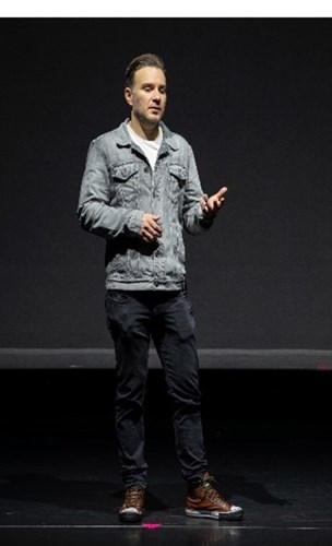 Brooke Trotter stood on stage against a black background speaking to the audience