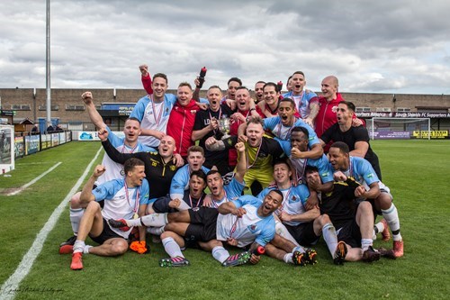 A group GMFRS male football players celebrating on the field, with many smiling and cheering