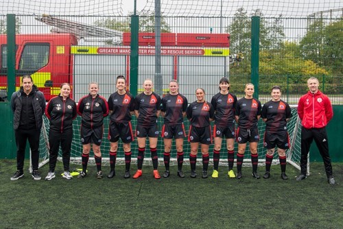 Women's GMFRS football team in matching black and red kits in front of a goalpost