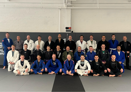 A group photograph of the GMFRS Brazilian Jiu-Jitsu team. There are 29 members sat in three staggered rows.